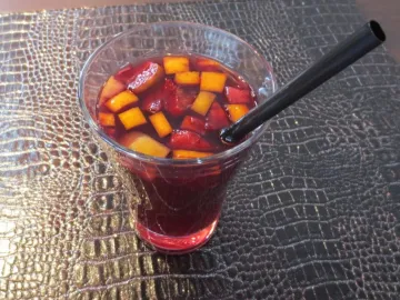 Красная сангрия с кубиками апельсина и яблока в стакане