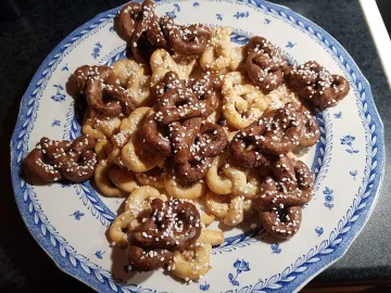 Светлые и шоколадные крендельки с крупным сахаром на тарелке