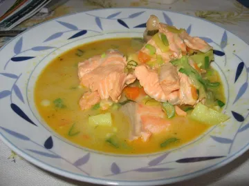 Тарелка сливочного супа с кусочками лосося и овощами
