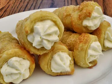 Слоёные трубочки с белым кремом и сахарной корочкой на тарелке