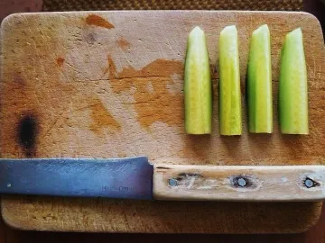 Нарезанный огурец и нож на деревянной разделочной доске