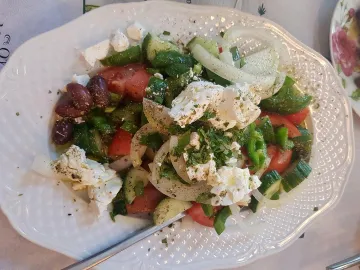 Греческий салат с фетой, оливками, помидорами и огурцами на белой тарелке