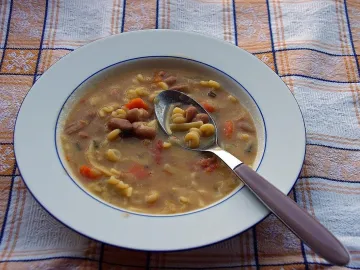 Суп с красной фасолью, макаронами и морковью в тарелке с ложкой