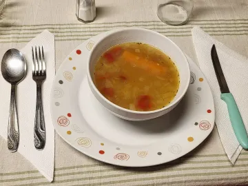 Лёгкий овощной суп с морковью и помидором в белой тарелке
