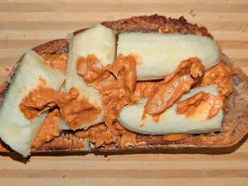 Тост с арахисовой пастой и кусочками банана на доске