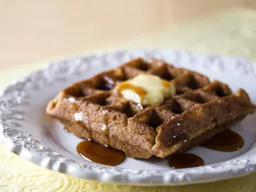Вафля со сливочным маслом и сиропом на белой тарелке