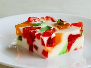 Кусок желе с цветными кубиками в белой сметанной заливке