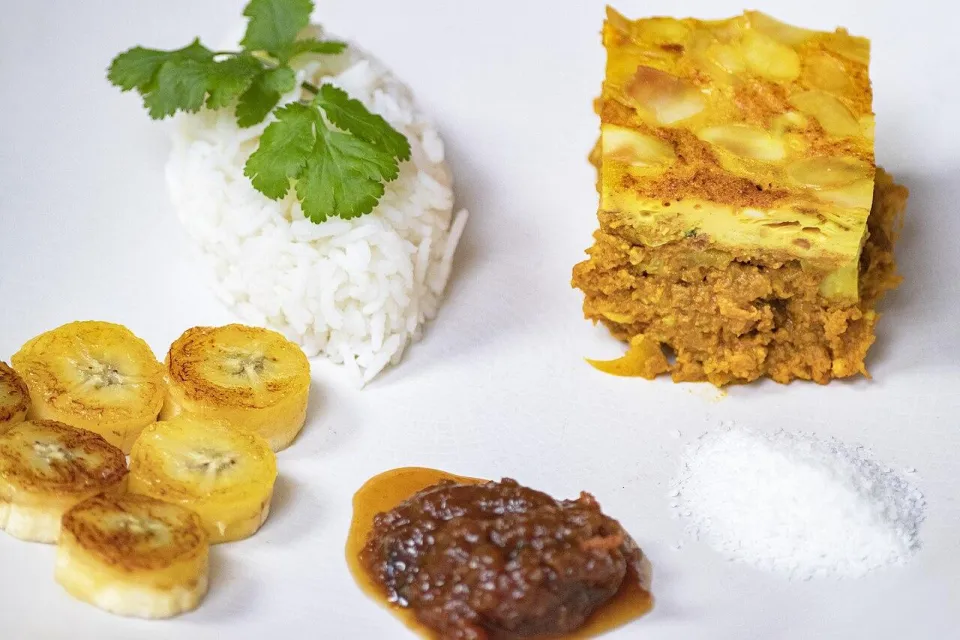 Кусок боботи с рисом, жареным бананом и чатни на тарелке