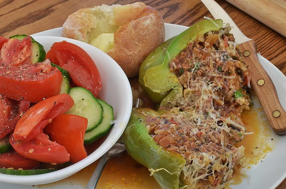 Фаршированные зелёные перцы с мясом и рисом на тарелке с салатом