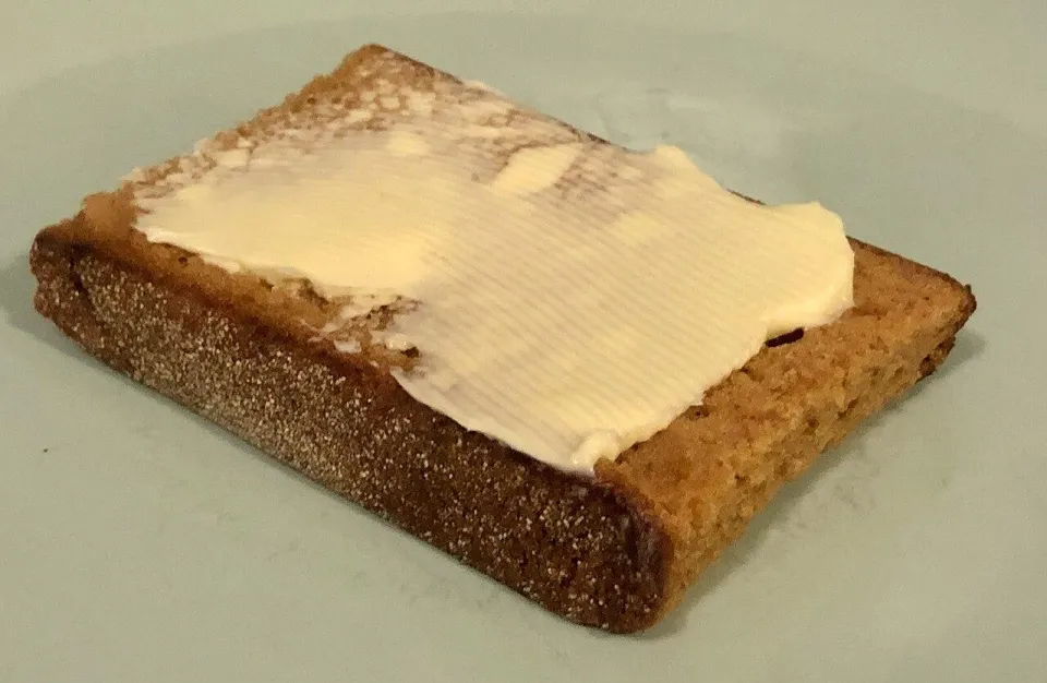 Ломоть голландской пряничной коврижки со сливочным маслом на тарелке
