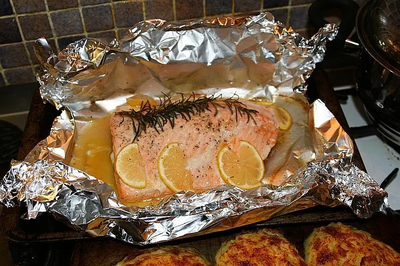 Кусок запечённой красной рыбы с лимоном и розмарином в фольге