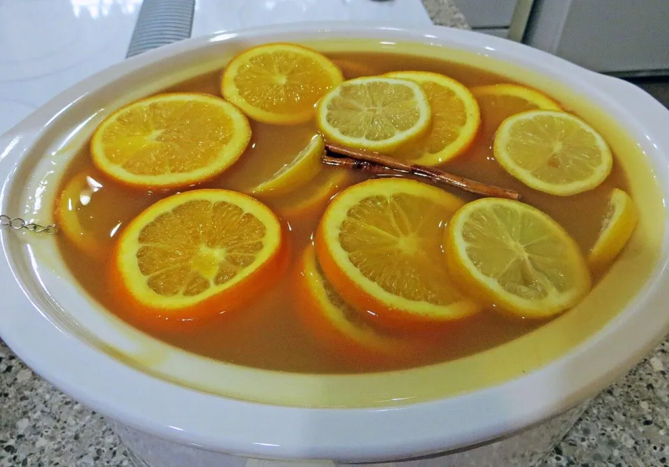 Горячий яблочный пунш с кружками апельсина, лимона и корицей