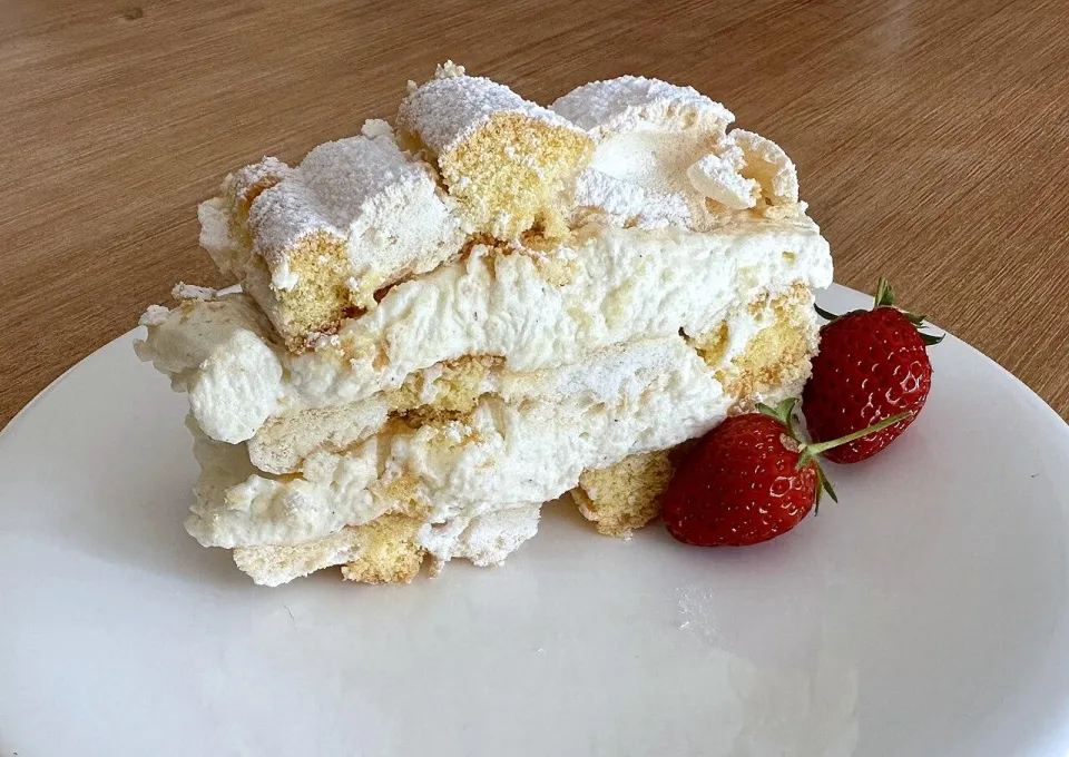 Кусок кардинальского пирожного со сливками и клубникой на тарелке