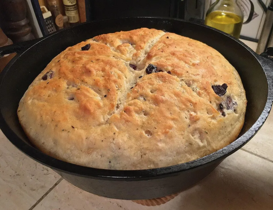 Круглый хлеб с оливками в чугунной форме, золотистая корка