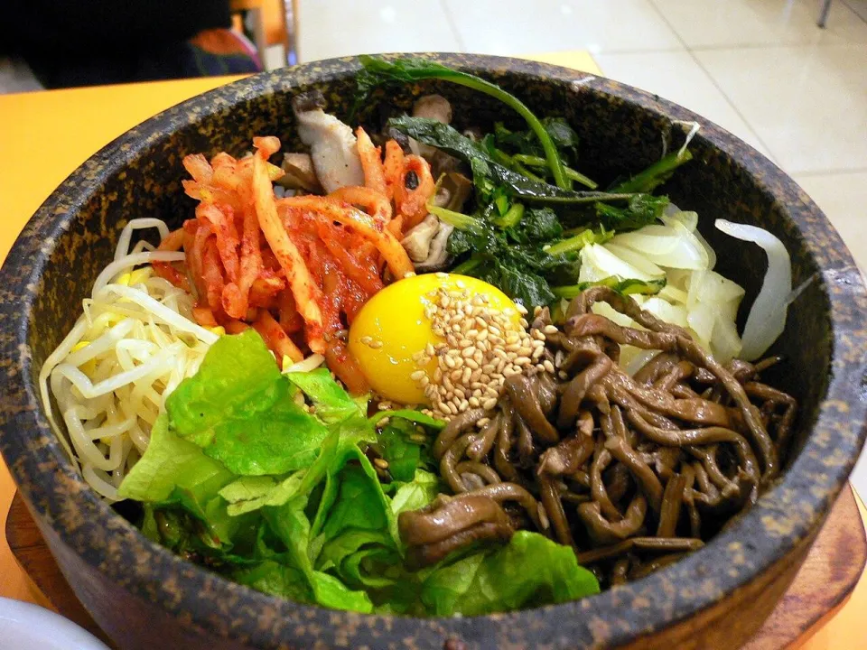 Бибимбап в каменной миске с овощами, ростками фасоли, кимчи и яйцом