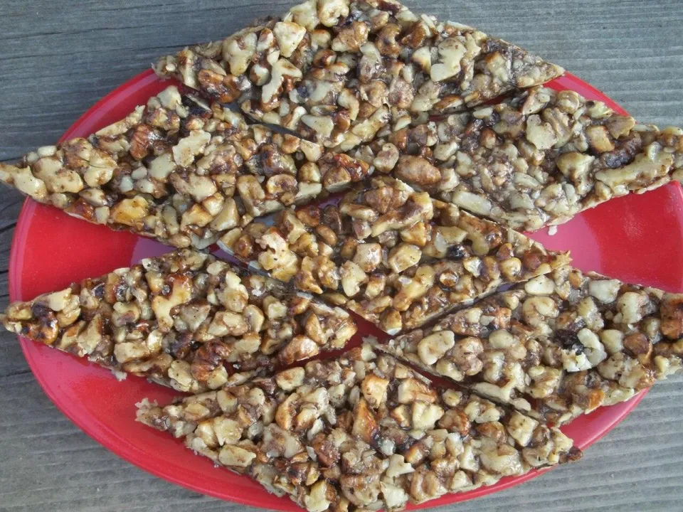 Козинаки из грецких орехов ромбами на красной тарелке