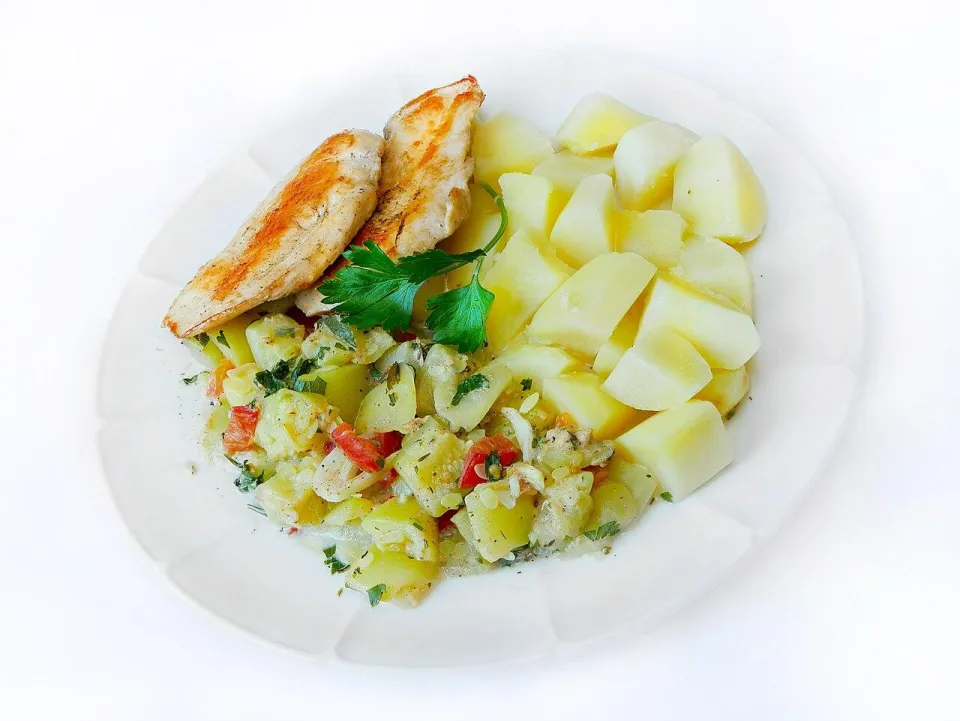 Обжаренное куриное филе, тушёные кабачки и отварной картофель на белой тарелке