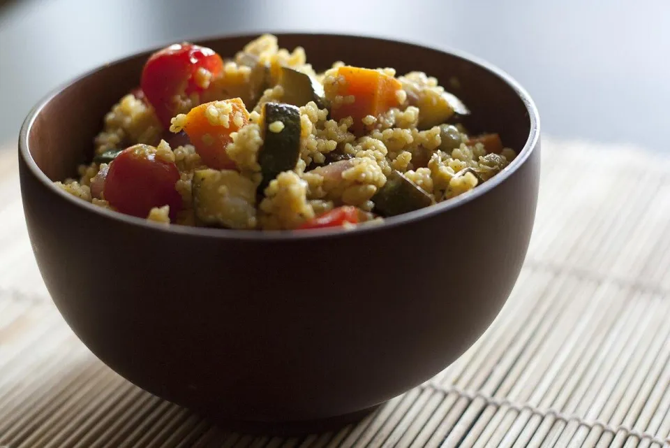 Кускус с кабачком, морковью и помидорами черри в коричневой миске