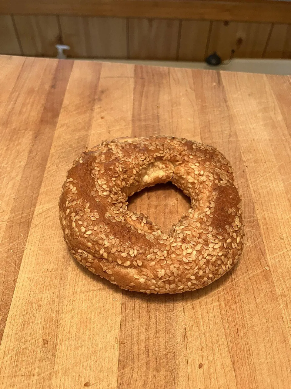 Монреальский бейгл, густо покрытый кунжутом, на деревянной доске