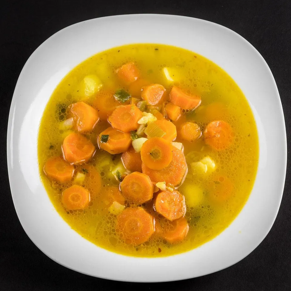 Морковный суп с кружками моркови и картофелем в белой тарелке