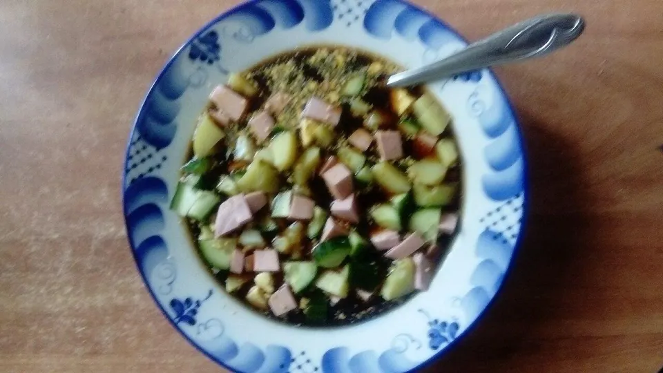 Окрошка на квасе с колбасой и огурцами в тарелке