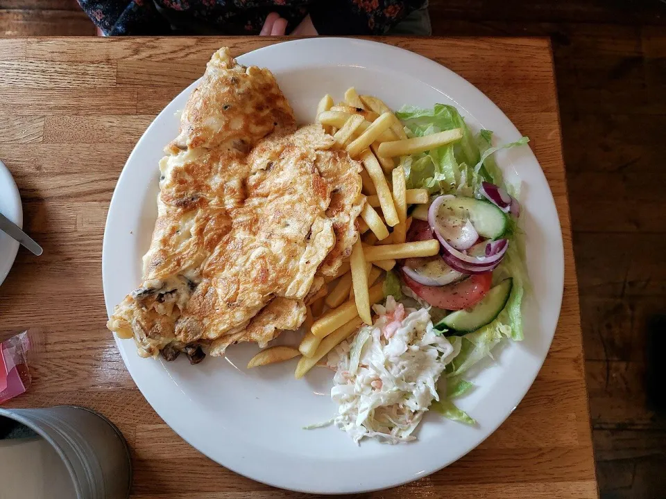 Сложенный пополам румяный омлет с сыром и грибами на тарелке