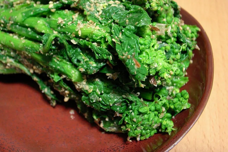 Зелёные овощи, посыпанные кунжутным соусом гомаэ, на коричневой тарелке