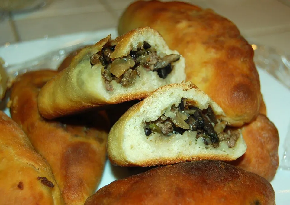 Разломленные пирожки с начинкой из фарша и грибов