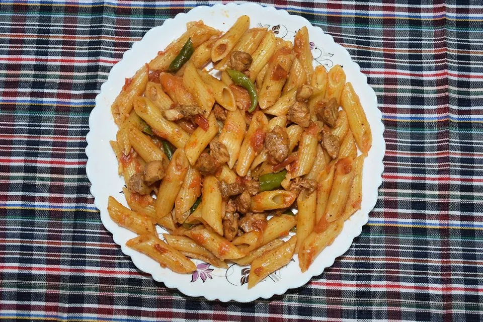Паста пенне с курицей и томатным соусом на тарелке