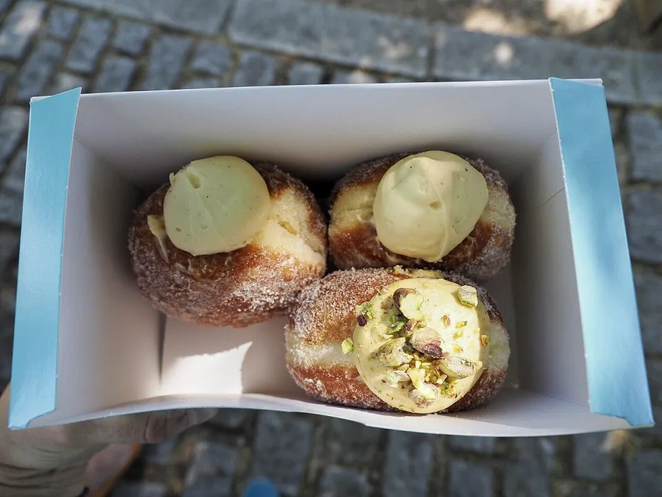 Три пончика в сахаре с фисташковым кремом в картонной коробке