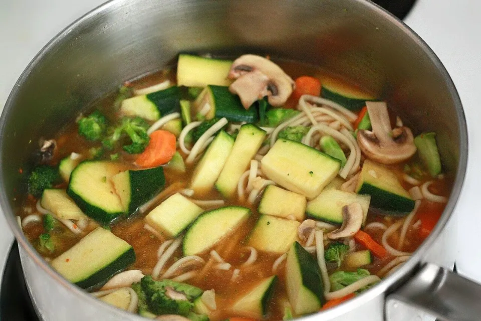 Кастрюля супа с лапшой удон, кабачком, брокколи и шампиньонами