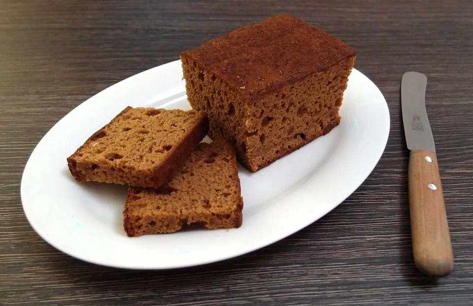 Ржаная медовая коврижка, нарезанная ломтями на белом блюде