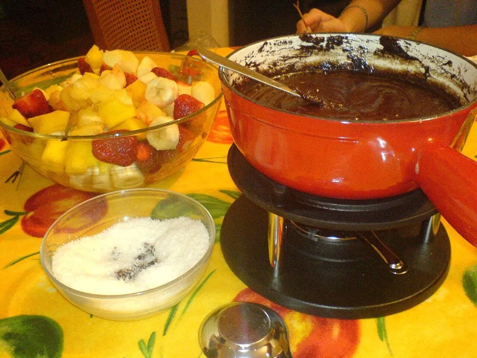 Шоколадное фондю в кастрюльке, миска фруктов и кокосовая стружка