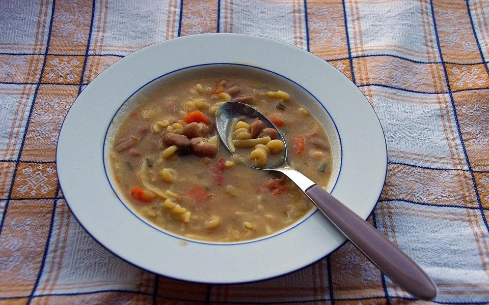 Суп с красной фасолью, макаронами и морковью в тарелке с ложкой