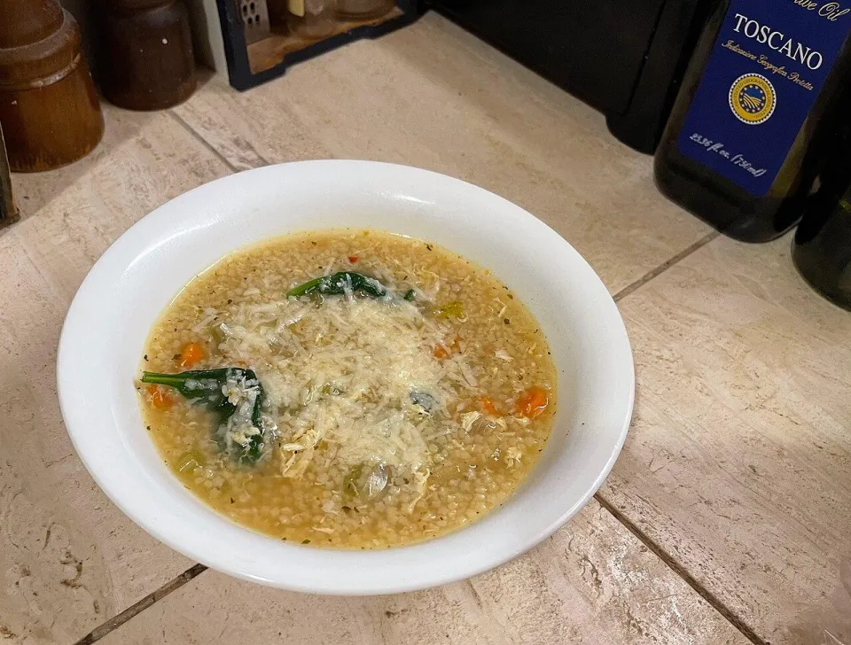 Суп с мелкой вермишелью, шпинатом и курицей, посыпанный тёртым сыром