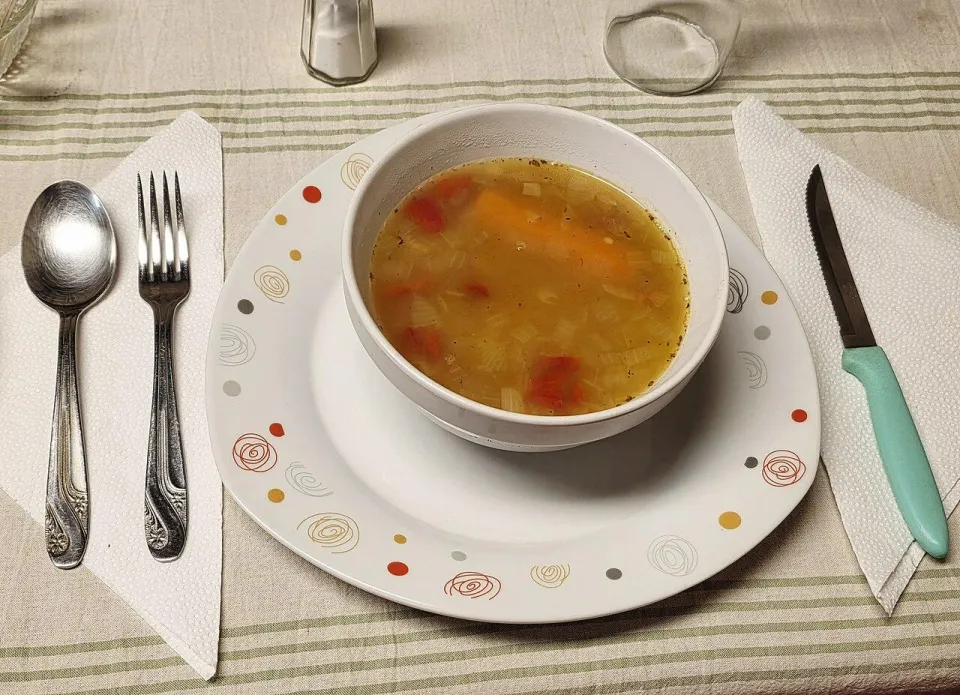 Лёгкий овощной суп с морковью и помидором в белой тарелке