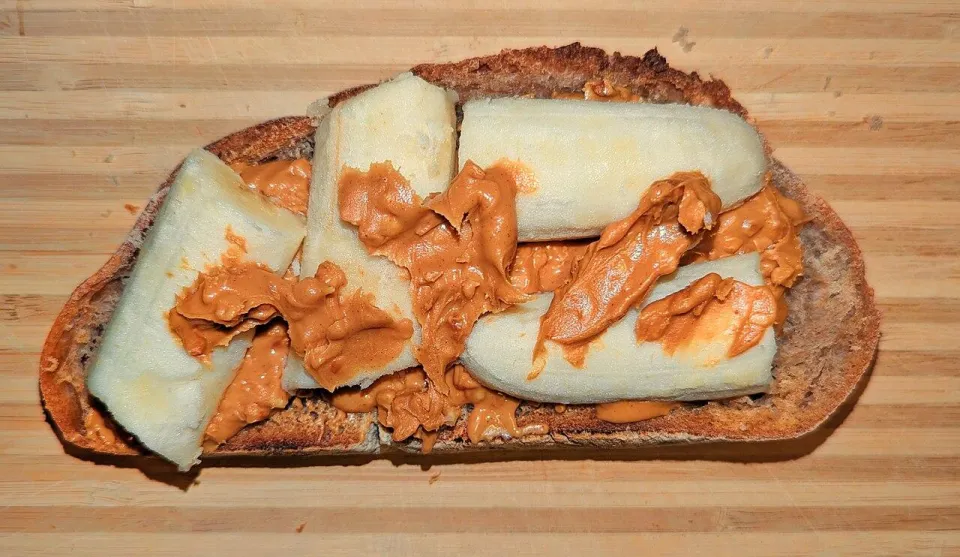 Тост с арахисовой пастой и кусочками банана на доске