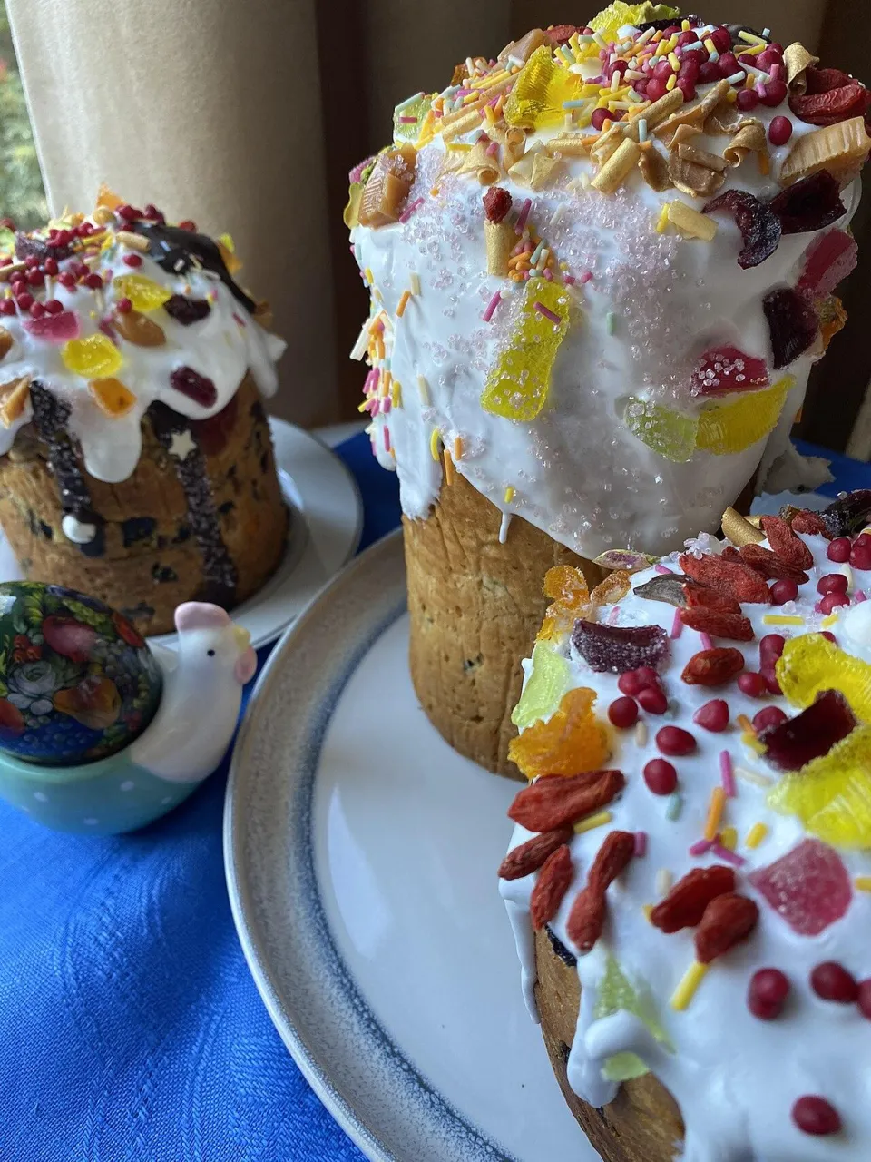 Круглая творожная пасха с изюмом, куличи с сахарной пудрой и крашеные яйца на столе