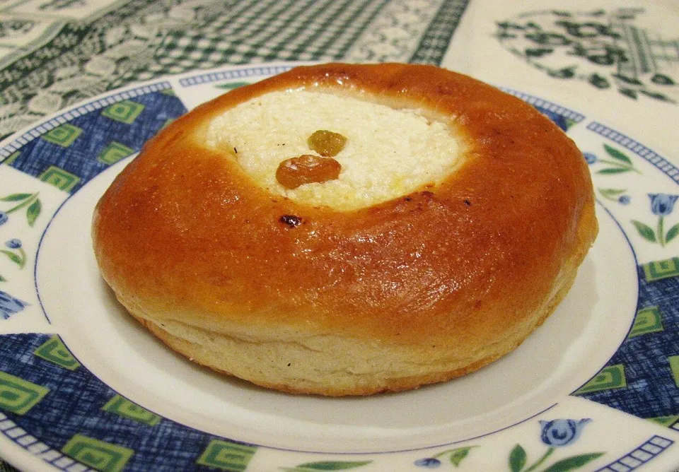 Ватрушка с творогом и изюмом на тарелке