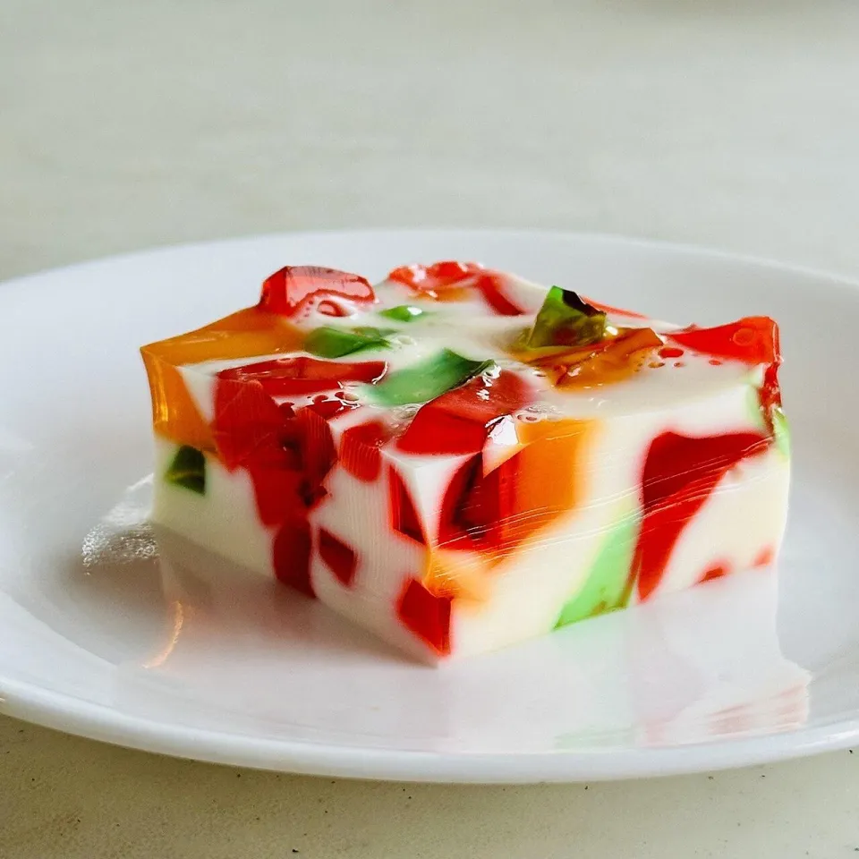 Кусок желе с цветными кубиками в белой сметанной заливке